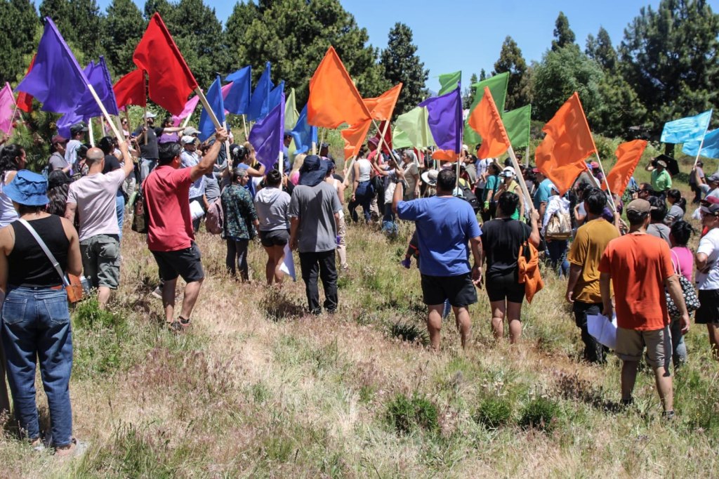 Vecinas y vecinos de De la Tierra al Barrio levantan banderas de colores en el terreno del futuro barrio, San Martín de los Andes
