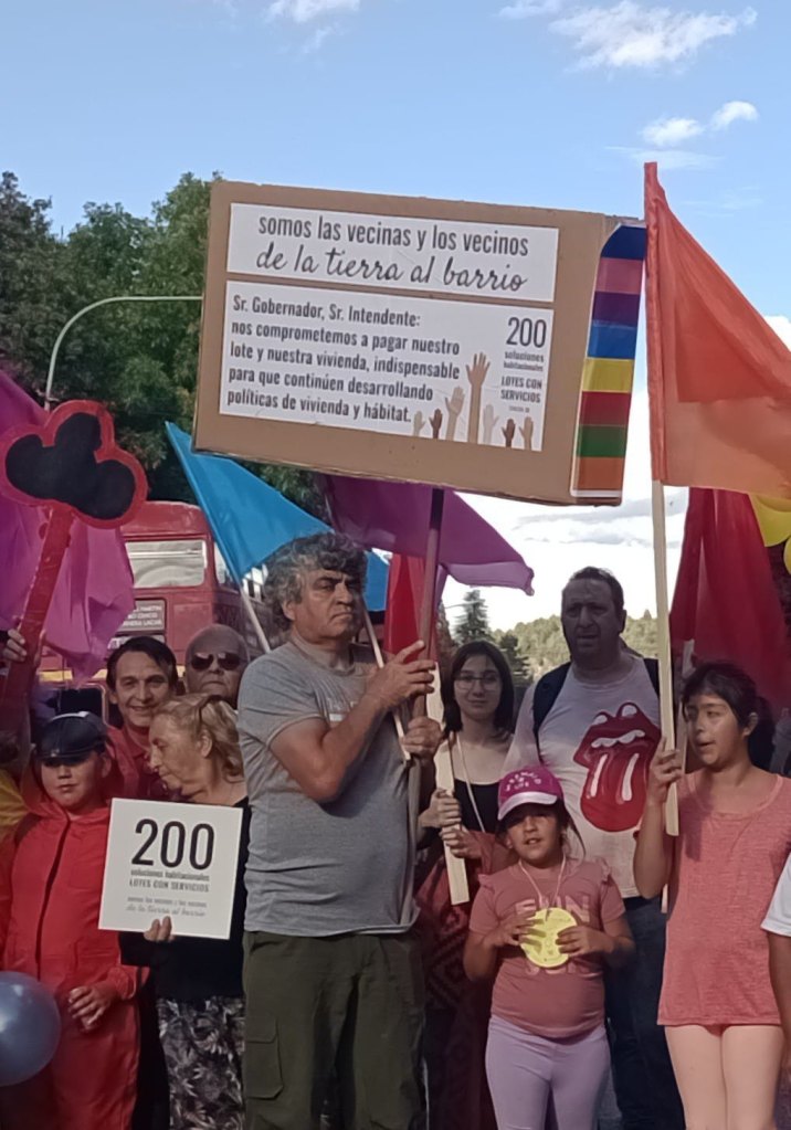 Vecinas y vecinos de De la Tierra al Barrio con un cartel por 200 soluciones habitacionales